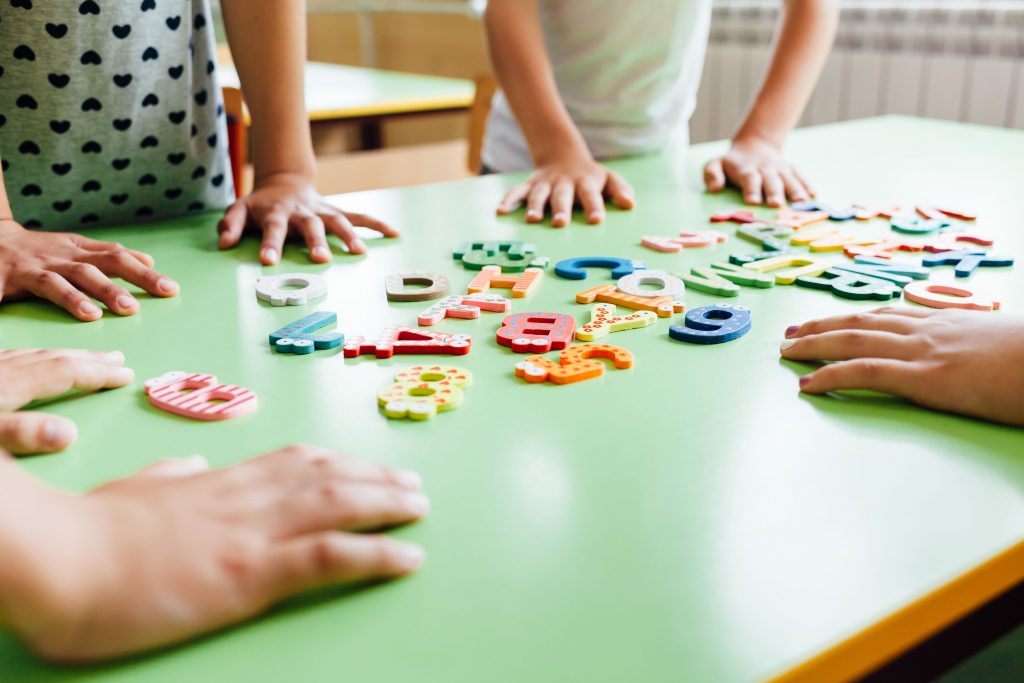 lettres colorées avec enfants autour d'une table verte