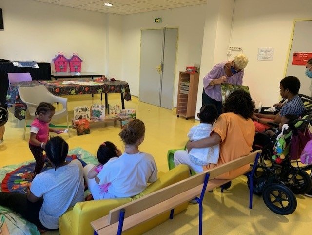 Photo d'enfants malades assis qui écoutent la lecture faite par une bibliothécaire