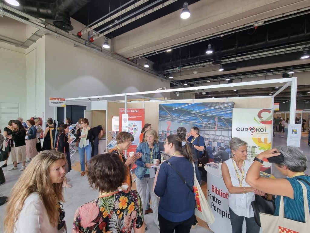 Photographie du stand de la Bpi au congrès 2022 de l'ABF avec des collègues qui échangent entre eux