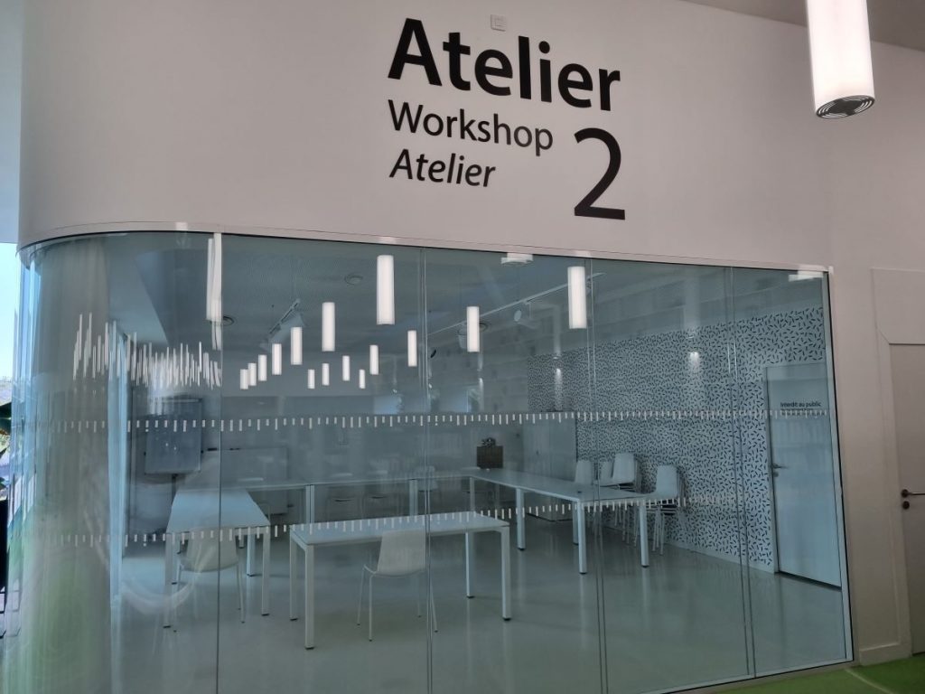 Photo d'un des ateliers vitrés avec tables, chaises et matériel de vidéoprojection à l'intérieur