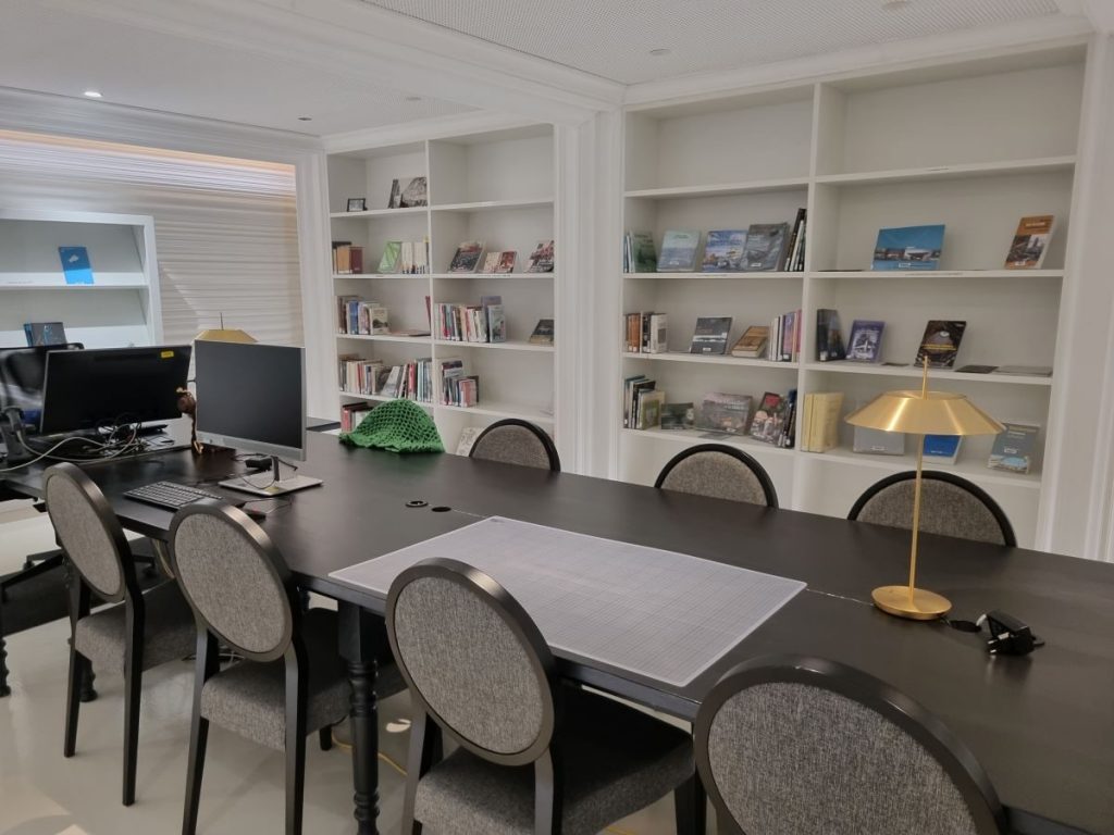 Photo de la salle patrimoine avec la grande table noire et les chaises, puis, au fond, les étagères