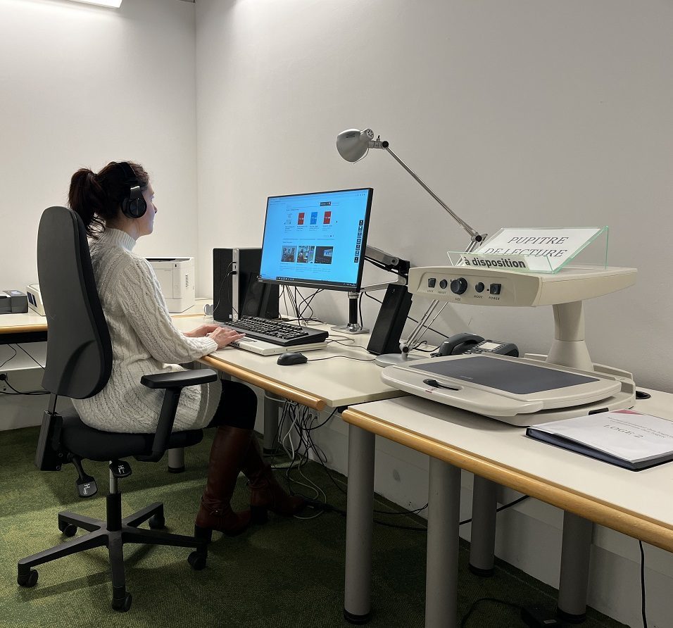 Du matériel d'aide à la lecture dans une loge. Une femme utilise l'ordinateur.