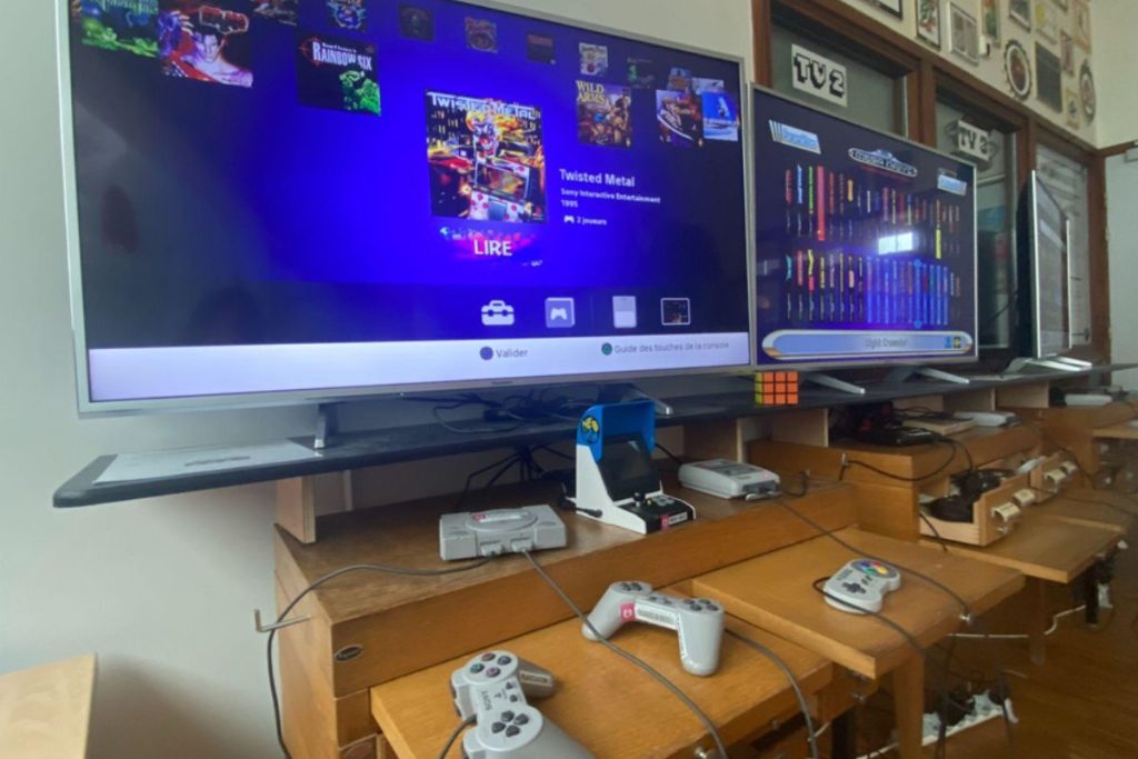 Deux grandes télés, une console PS1 avec deux manettes, une console super Nes avec une manette