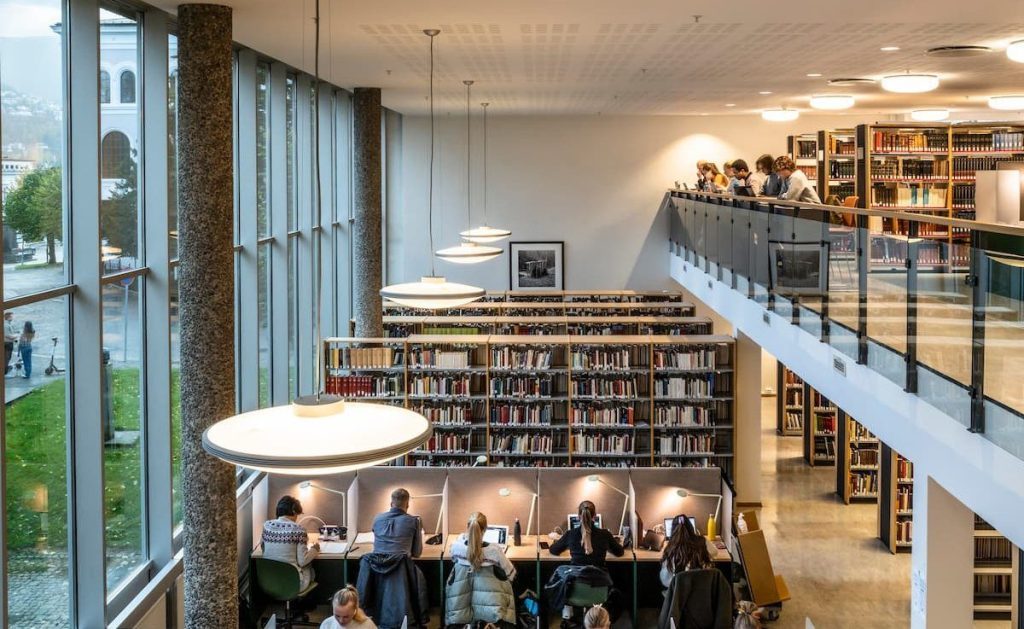 Bibliothèque de style contemporain, composée d'espaces de travail, de rayonnages de livres.