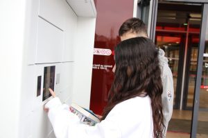 Deux adolescents retirent des documents dans un casier connecté à écran tactile