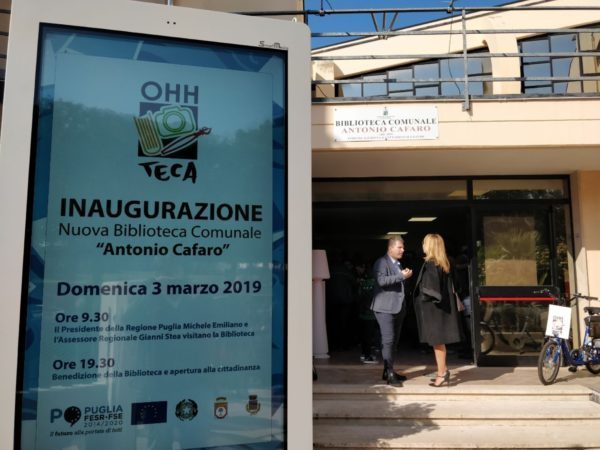 Façade de la bibliothèque municipale Antonio Cafaro à Adeldia dans la région italienne des Pouilles. Ecran informatif annonçant l'inauguration de la bibliothèque et les partenaires du projet, dont l'Union européenne et son drapeau.
