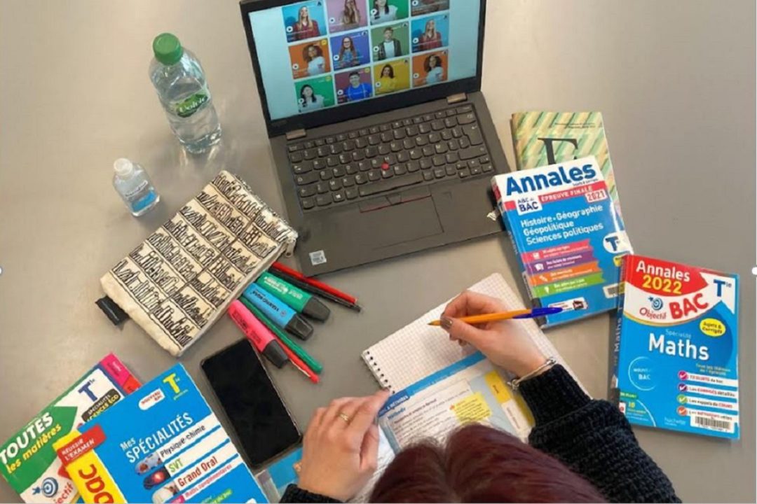 Table de révisions avec ordinateur, annales du bac, crayons.